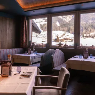 Gemütliches Alpenrestaurant mit Blick auf schneebedeckte Berge durch große Fenster