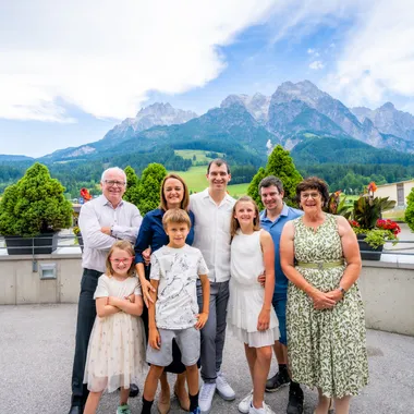 Lächelnde Familie posiert im Freien mit Alpen und bepflanzten Kübeln im Hintergrund