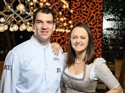 Lächelndes Paar in Tracht und Kochuniform in gehobenem Restaurant