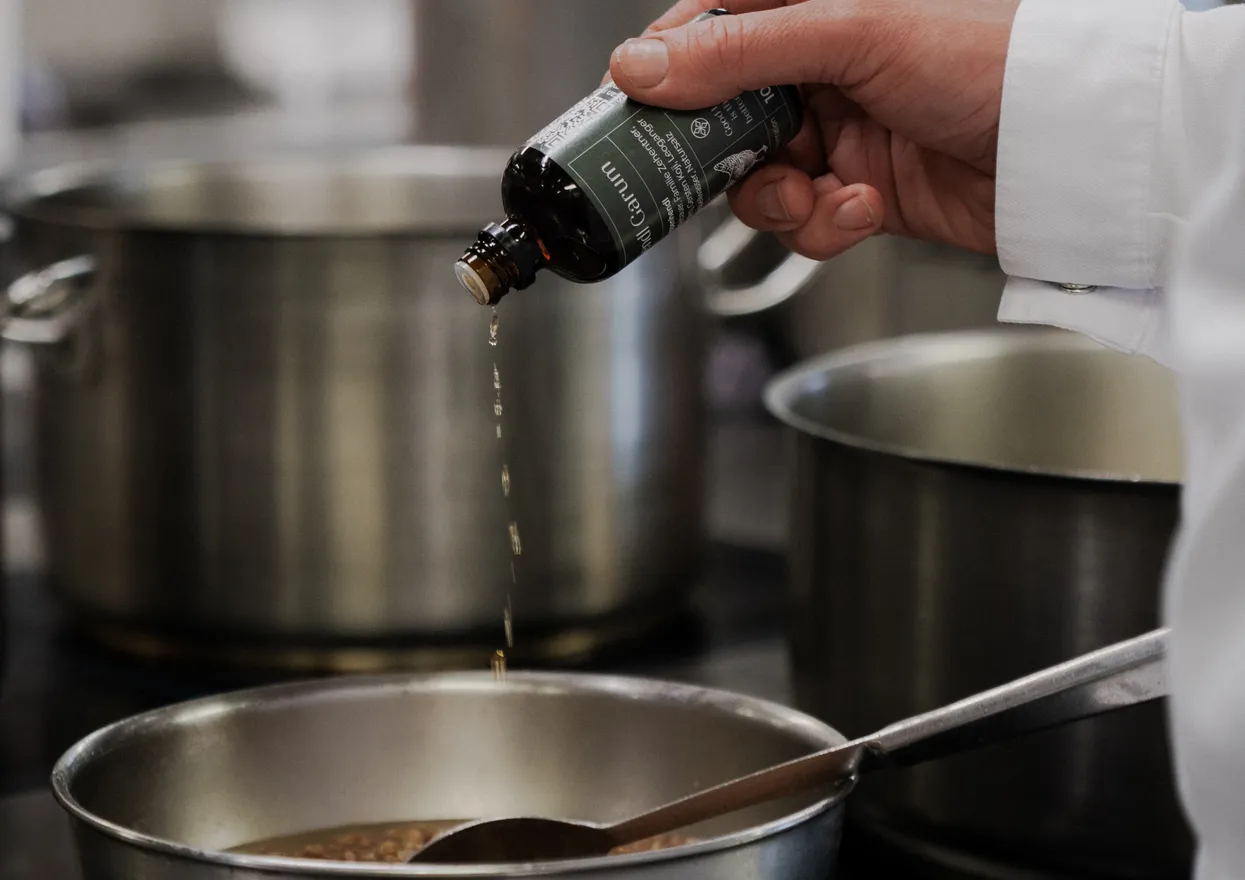 Chef adding liquid seasoning to saucepan in professional kitchen