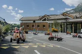 Kinder fahren Tretkarts auf einem Miniverkehrsübungsplatz vor Bergkulisse