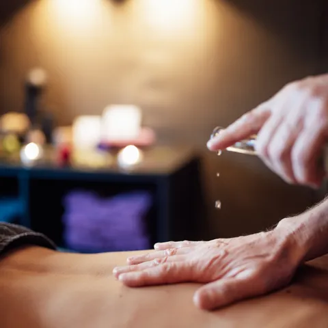 Massage oil being applied to back in relaxing spa setting