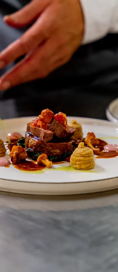 Koch richtet ein Gourmet-Rindfleischgericht mit Sauce und Püree kunstvoll an