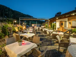Cozy outdoor restaurant terrace in the mountains with candlelit tables at dusk