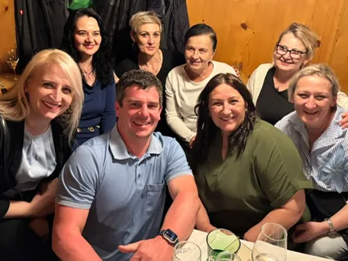 Gruppe lächelnder Erwachsener an einem Holztisch in einem gemütlichen Restaurant