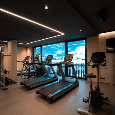 Modernes Fitnessstudio mit Cardiogeräten und Bergblick durch große Fenster