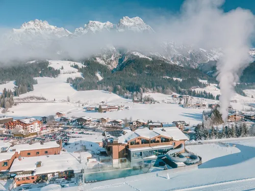 Sněhem pokrytá alpská vesnice s horami a wellness resortem v zimní krajině