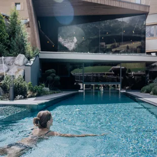 Woman swimming in a luxurious outdoor pool at a modern wellness hotel