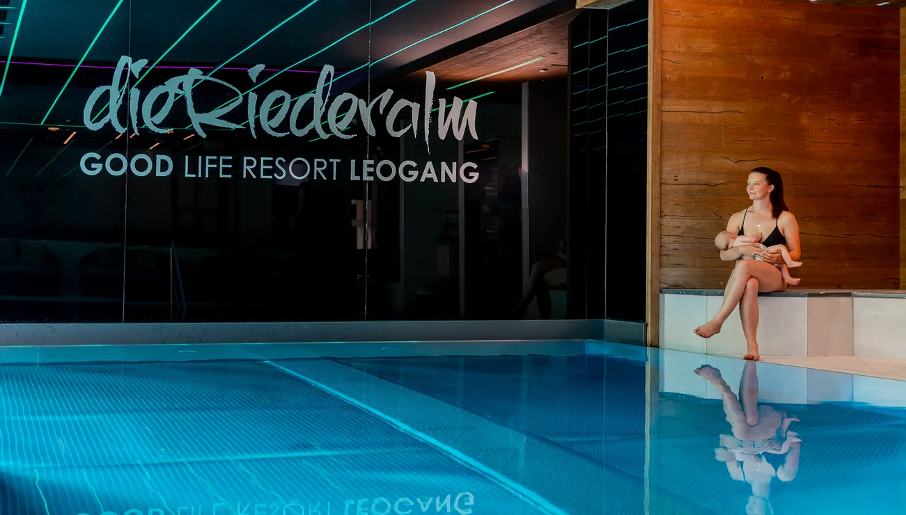 Mutter mit Baby entspannt am Innenpool im Good Life Resort Leogang