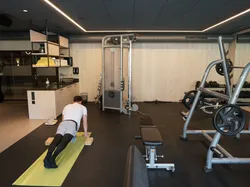 Mann macht Plank-Übung auf Yogamatte in modernem Fitnessstudio mit Trainingsgeräten
