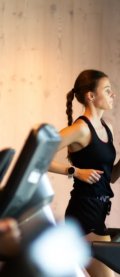 Frau und Mann laufen auf Laufbändern in modernem Fitnessstudio