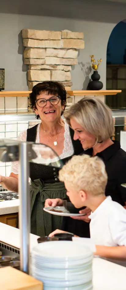 Family at hotel breakfast buffet being served by a smiling staff member