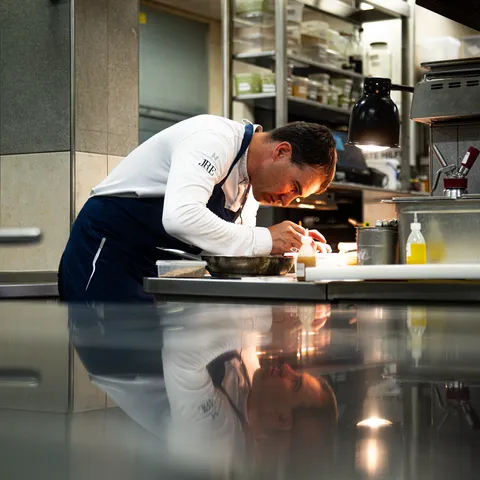 Chef plating gourmet dish with precision in a professional kitchen