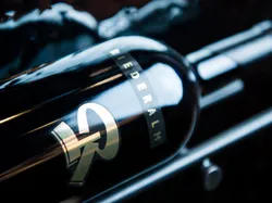 Dark wine bottle labeled Riederalm in elegant rack with reflective lighting