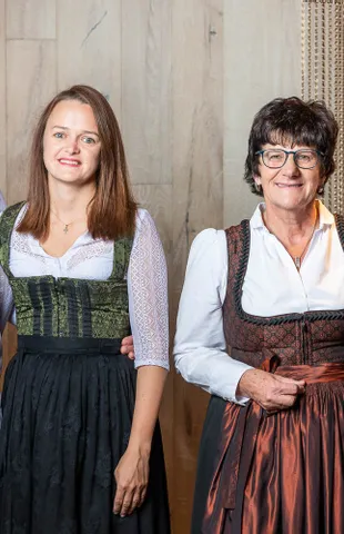 Group of four people in traditional Austrian attire and a chef uniform smiling indoors