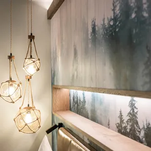 Rustic pendant lights with rope above wooden headboard and forest wall art