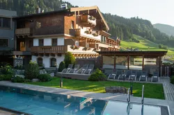 Luxury alpine hotel with outdoor pool and mountain view at sunset