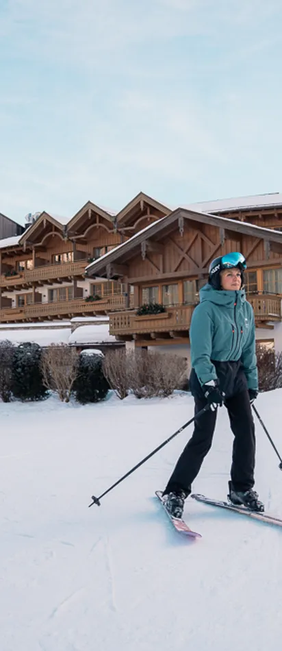 Skier on snowy slope in front of alpine ski resort with wooden chalet buildings