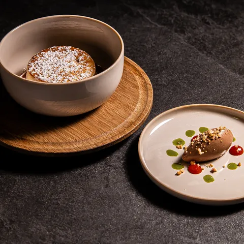 Chocolate soufflé with powdered sugar and chocolate mousse with sauce drops on stone background