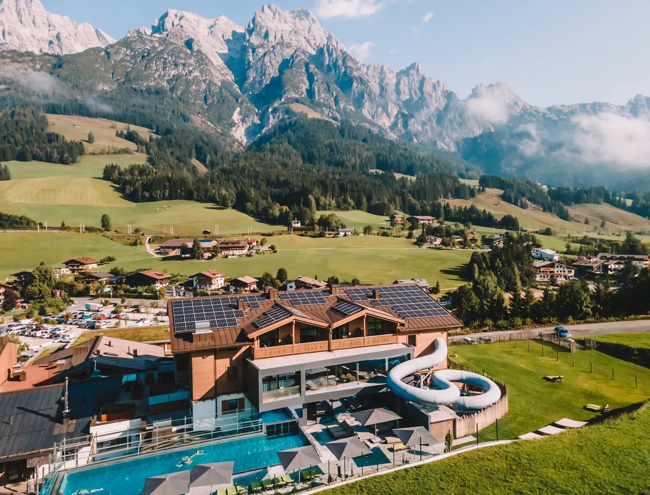 Luxuriöses Alpenresort mit Pool und Wasserrutsche vor Bergkulisse