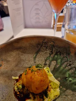 Gourmet dish with filled dumpling on cabbage and sauce in ceramic bowl