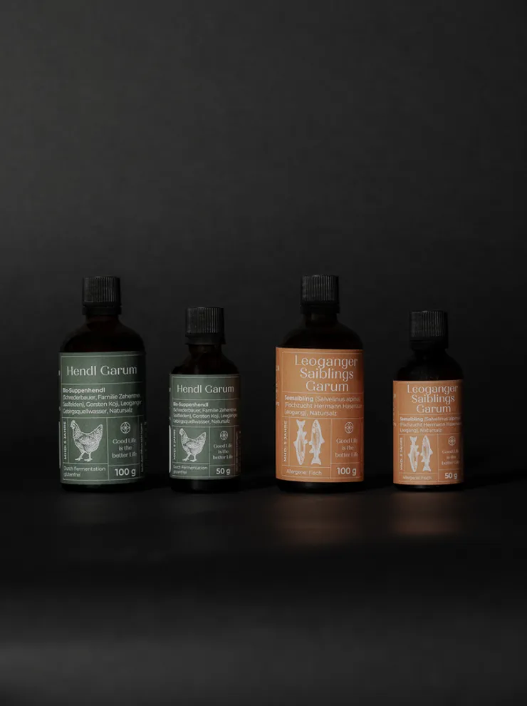 Four glass bottles of organic Hendl Garum and Saiblings Garum sauces on dark background