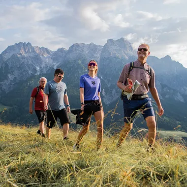Gruppe von Wanderern auf einem grasbewachsenen Pfad mit malerischem Bergblick im Hintergrund