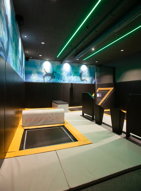 Indoor-Trampolinpark bei Riederalm mit gepolsterten Böden und Neonbeleuchtung