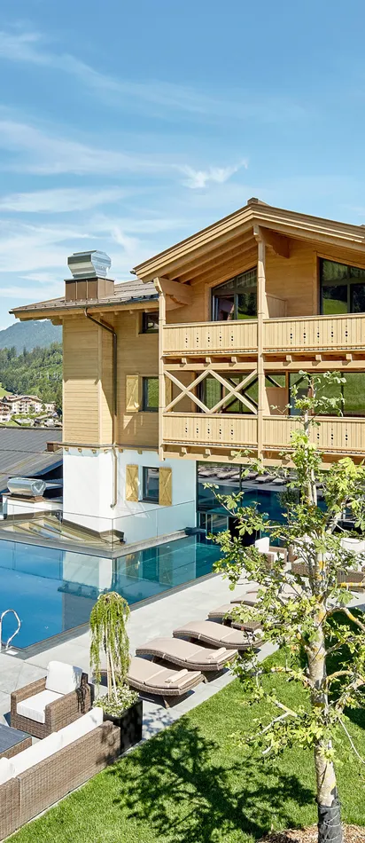 Familienhotel mit Außenpool, Sonnenliegen und Wasserrutsche in alpiner Berglandschaft