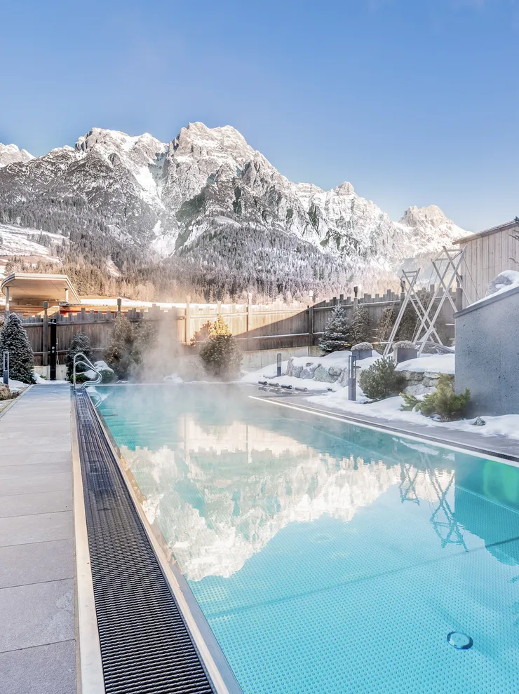 Beheizter Außenpool im verschneiten Alpenresort mit Bergblick