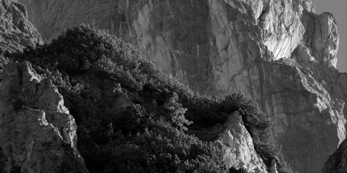 Steiler felsiger Berggipfel mit spärlicher Vegetation unter klarem Himmel
