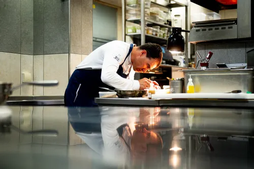 Konzentrierter Koch richtet ein Gericht sorgfältig in einer Profiküche an