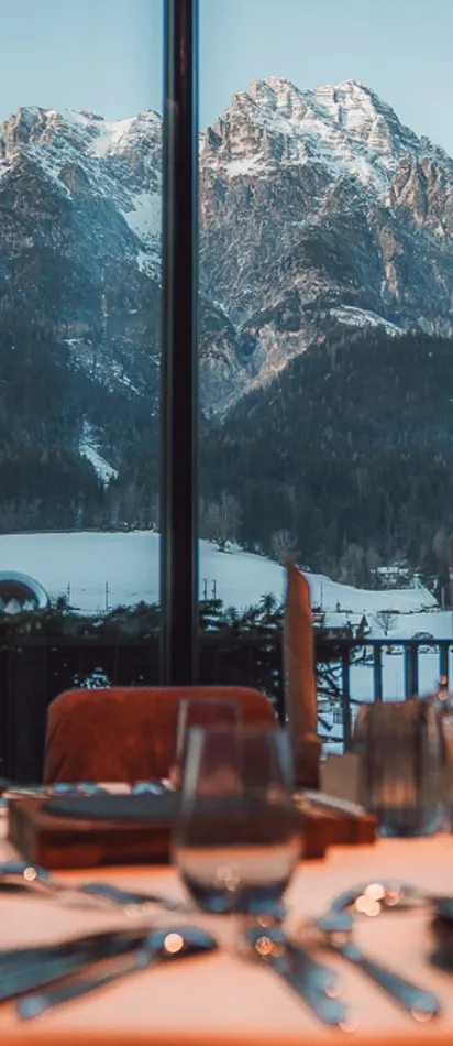 Elegant restaurant table set with view of snow-covered Alps through large window