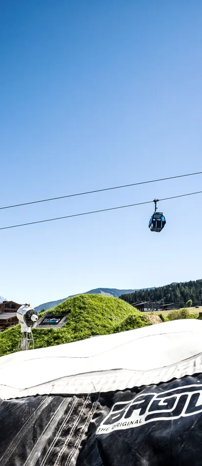 Mountain biker performing backflip stunt over airbag in alpine bike park
