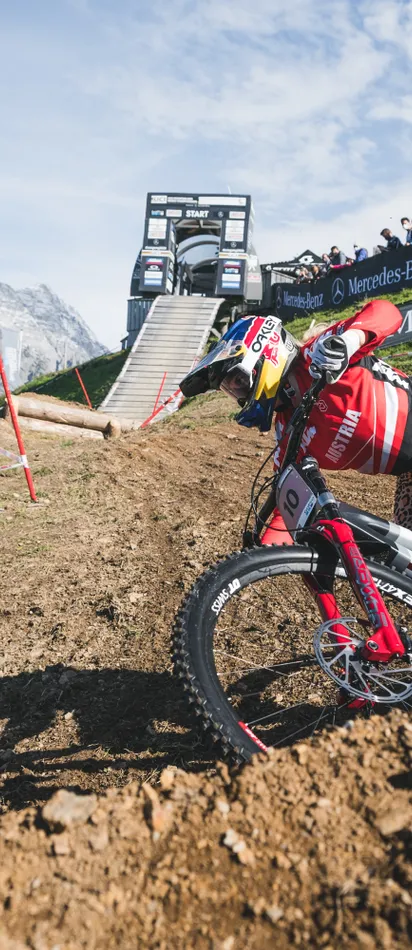 Downhill-Mountainbiker im Austria-Trikot fährt durch eine Kurve auf einem Bergtrail