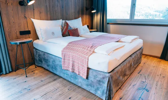 Cozy hotel room with double bed, wooden floor and modern lighting near a window