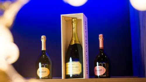 Champagne bottles of Ruinart and Bruno Paillard displayed on a shelf with blue background