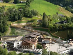 Alpine village with hotels and cable car station surrounded by green hills and forest