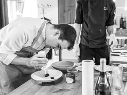 Chef precisely plating food with squeeze bottle in a professional kitchen