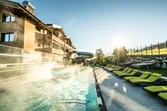 Outdoor heated hotel pool with sun loungers and water slide at sunrise