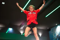 Child jumping with arms outstretched on indoor trampoline in modern trampoline park