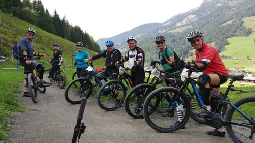 Group of mountain bikers posing on trail with scenic alpine landscape in background