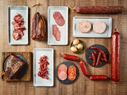 Verschiedene Wurstwaren und Aufschnitte auf Tellern und Brettern auf Holztisch