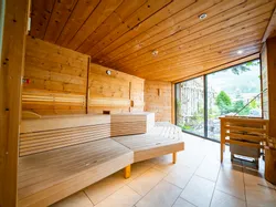 Modern wooden sauna room with scenic mountain view through large glass window