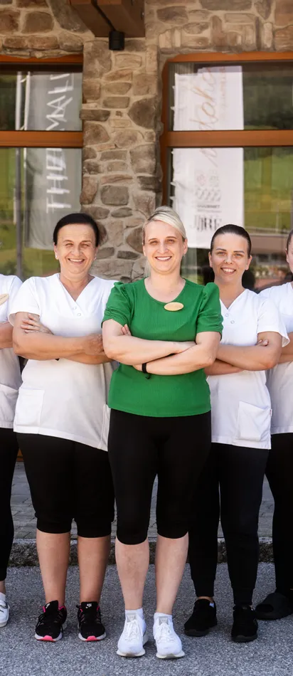Hauskeeping-Team in Arbeitskleidung steht lächelnd vor einem Hotelgebäude