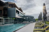 Modernes Berghotel mit Außenpool, Wasserrutsche und Sonnenliegen an einem sonnigen Tag
