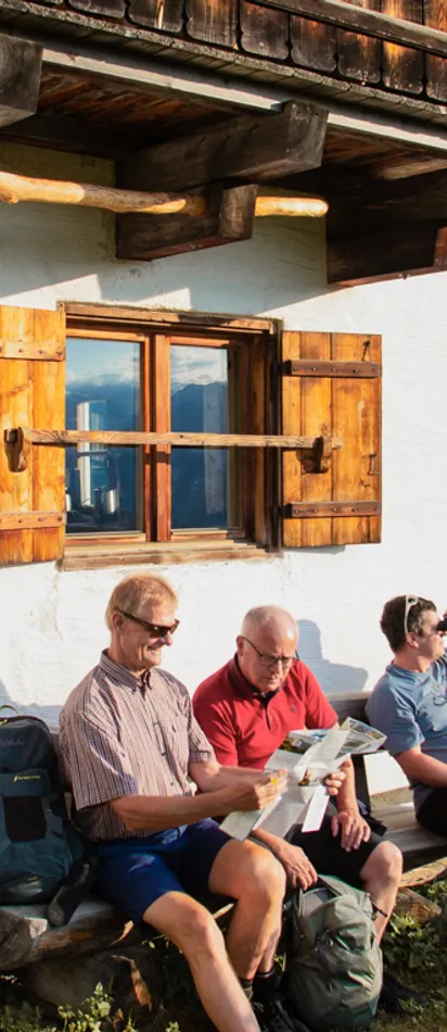 Hikers relaxing at a mountain hut with scenic alpine view at sunset