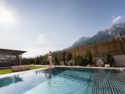 Woman in bikini entering outdoor pool at luxury hotel with mountain view