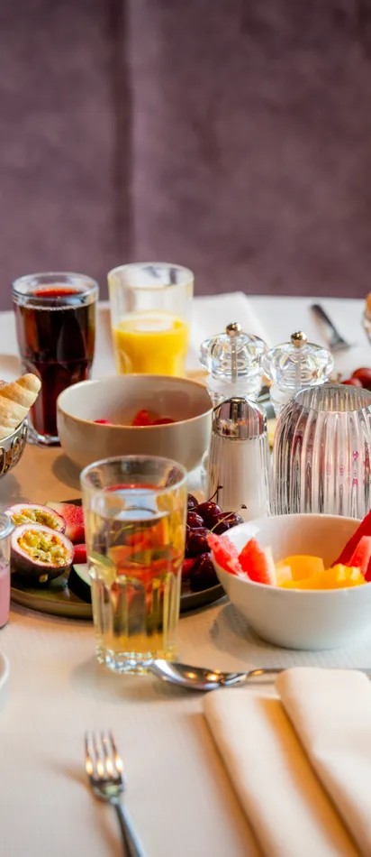 Elegant breakfast table with fresh fruit, pastries, juice, coffee, and cold cuts