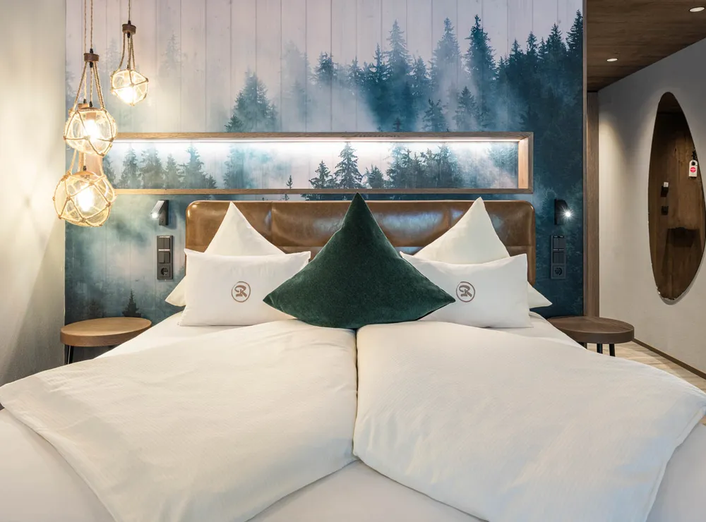Modernes Hotelzimmer mit Doppelbett, Wald-Wandbild und Hängelampen aus Seil